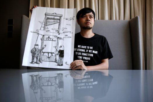 Political illustrator Ah To poses with his work "Guillotine" after his cartoon column in one of the city's popular news magazines was to be axed in Hong Kong, China, on July 28, 2020. (Tyrone Siu/Reuters)