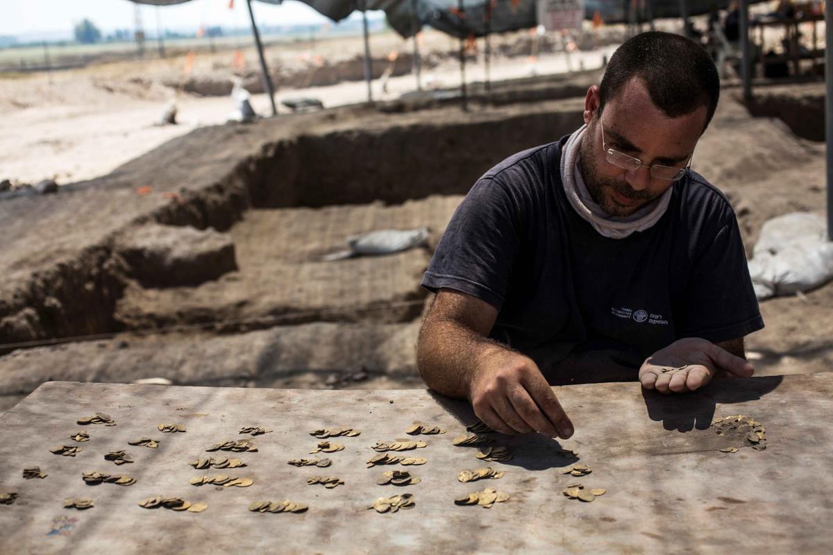 Israeli archeologist Shahar Krispin counts gold coins, said by the Israel Antiquities Authority to date to the Abbasid dynasty, after their discovery at an archeological site in Central Israel Aug. 18, 2020. (Heidi Levine/Pool via REUTERS)