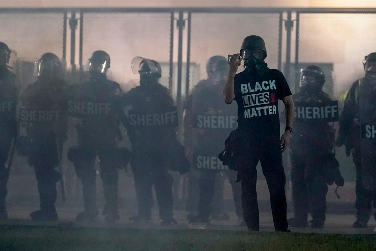 A protester holds up a phone as he stands in front of law enforcement officers in Kenosha, Wis., on Aug. 25, 2020. (Morry Gash/AP Photo)