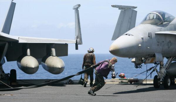 A U.S. Navy crewman pulls a fuel pipe across the deck of the USS Kitty Hawk (CV63) aircraft carrier during a Malabar exercise in the Bay of Bengal on Sept. 7, 2007. (Deshakalyan Chowdhury/AFP via Getty Images)