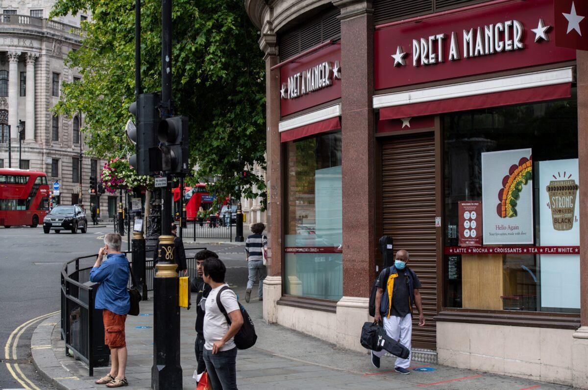 A musician wearing a face mask walks past a currently closed Pret a Manger restaurant in Trafalgar Square, London, on July 6, 2020. (Chris J Ratcliffe/Getty Images)