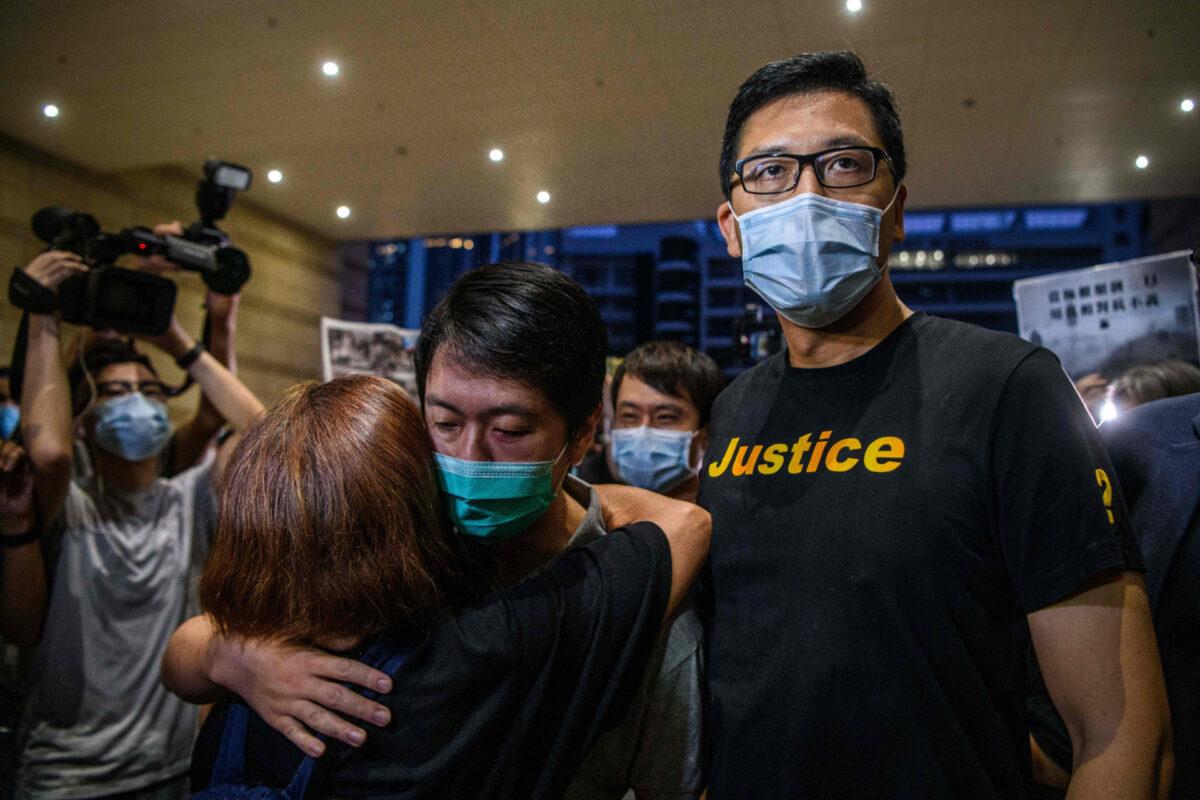 Pro-democracy lawmakers Ted Hui (C) is hugged by a supporter as he and Lam Cheuk-ting (R) leave the West Kowloon Magistrates Court on Aug. 27, 2020, after being granted bail following their arrest the day before in a police operation focused on last year's huge protests. (Anthony Wallace/AFP via Getty Images)