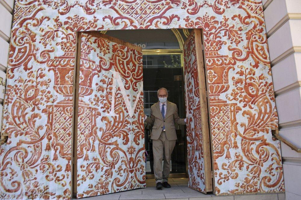 David Margulis, owner of Margulis Jewelers, emerges from a double layer of plywood doors he had installed to protect his store from protests that have dominated the city of Portland, Ore., since late May, on July 13, 2020. (Gillian Flacus/AP Photo)