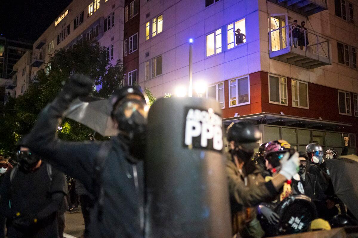 Residents of South Waterfront watch as officers disperse a crowd of about 200 that had been vandalizing a federal building, in Portland, Ore., on Aug. 26, 2020. (Nathan Howard/Getty Images)