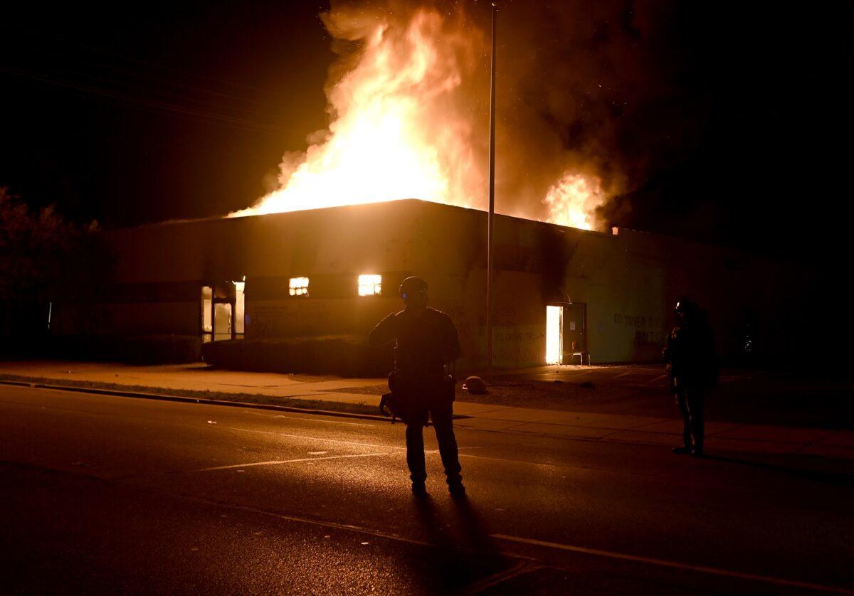 Flames engulf the Community Corrections Division building as police officers watch during rioting in Kenosha, Wis., on Aug. 24, 2020. (Stephen Maturen/Reuters)