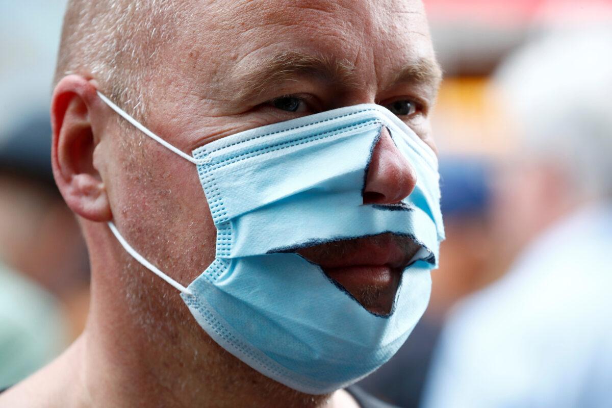 A demonstrator wears a mask that has been cut out as he attends a rally against the government's restrictions following the CCP virus disease (COVID-19) outbreak, in Berlin, Aug. 29, 2020. (Axel Schmidt /Reuters)