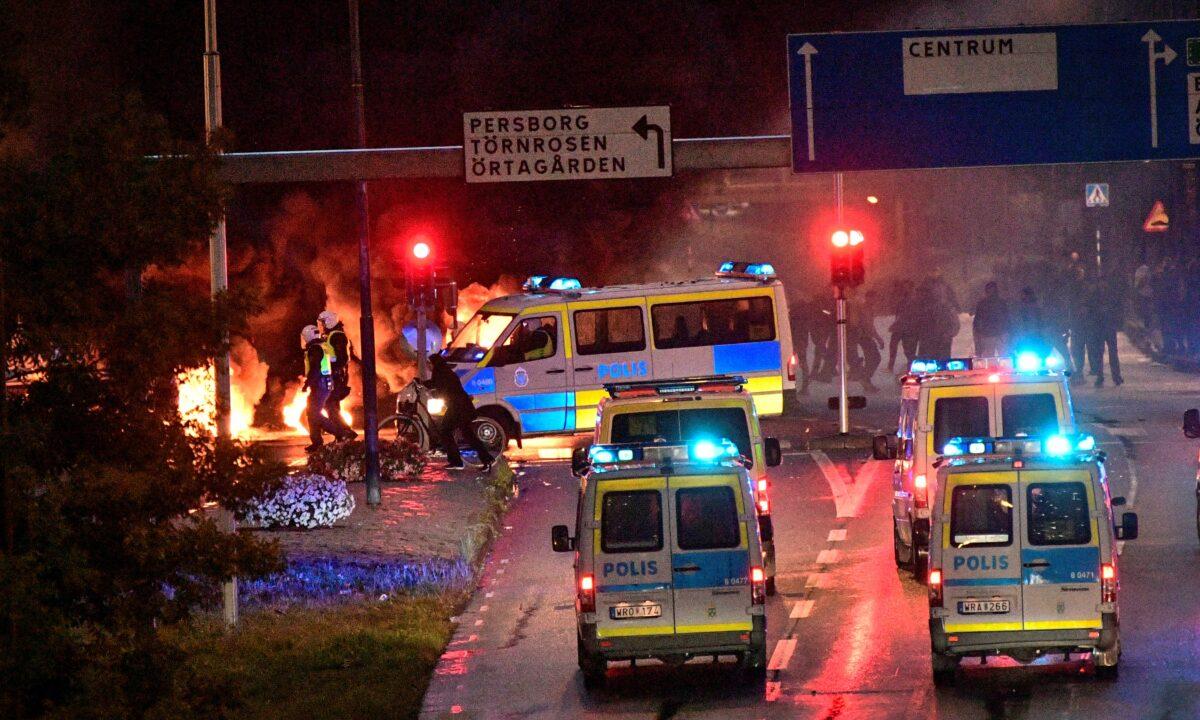 Police officers walk amid smoke from the burning tyres, pallets and fireworks during a riot in the Rosengard neighborhood of Malmo, Sweden, on Aug. 28, 2020. (TT News Agency via Reuters)