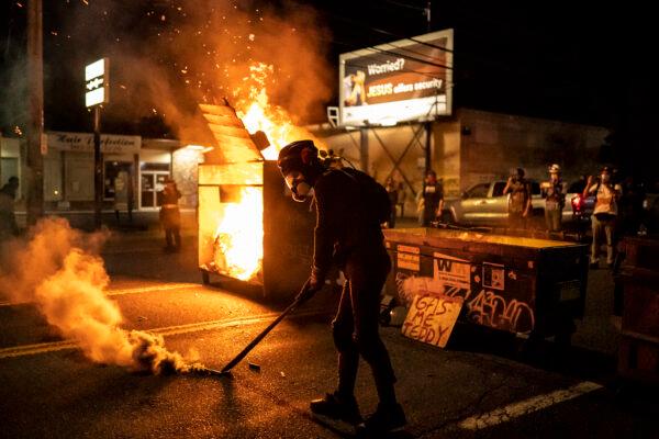 A protester walks past a dumpster fire early in the morning in Portland, Oregon on Aug. 29, 2020. (Nathan Howard/Getty Images)
