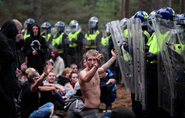 A reveller puts his hands up in front of riot police at the scene of a suspected illegal rave in Thetford Forest, in Norfolk, Britain on Aug. 30, 2020. (Reuters/Toby Melville)