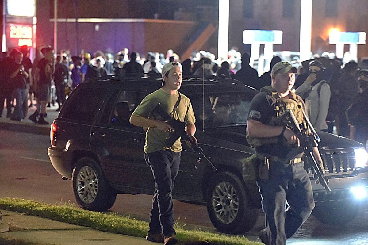 Kyle Rittenhouse (L) with backwards cap, walks along Sheridan Road in Kenosha, Wis., with another armed civilian., on Aug. 25, 2020. (Adam Rogan/The Journal Times via AP)