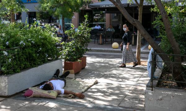 A woman looks at a migrant who has camped at central Victoria square in Athens, on Sep. 2, 2020. (Yorgos Karahalis/AP Photo)