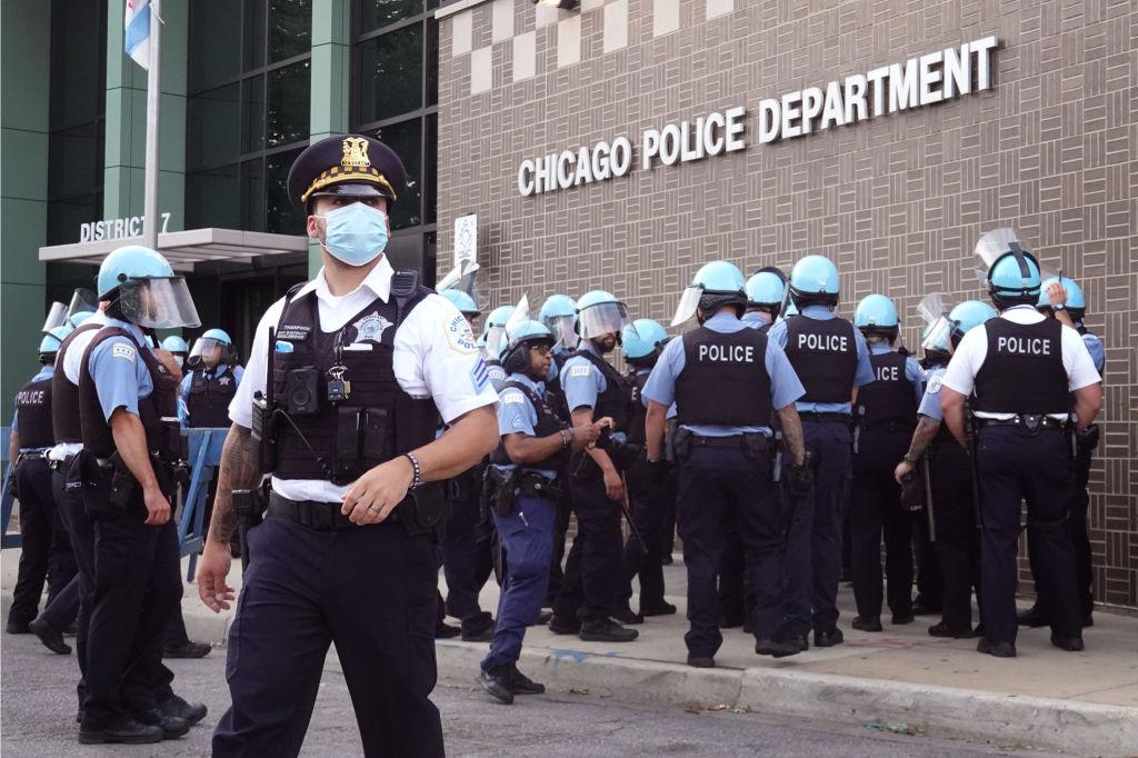 Chicago police stand guard as demonstrators protest outside the department's 7th District station in Chicago, Illinois, on Aug. 11, 2020. The protest was held in response to the August 9 shooting and wounding of a 20-year-old man who allegedly fired at officers in the Englewood neighborhood. The protest was met with resistance from a small group of Englewood residents. (Scott Olson/Getty Images)