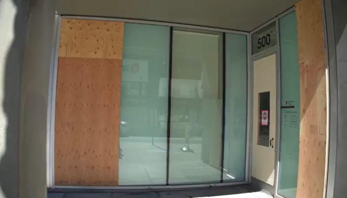 In this still image from video, boards cover glass panels destroyed recently by rioters, at Pearl District Dental, in Portland, Ore., on Sept. 2, 2020. (Roman Balmakov/The Epoch Times)