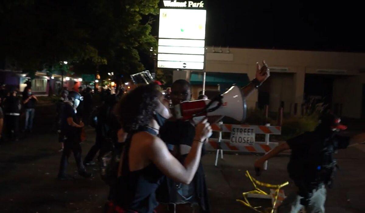In this still image from video, demonstrators remove barricades and tape from a street near the Portland Police Bureau's North Precinct, in Portland, Ore., on Sept. 2, 2020. (Roman Balmakov/The Epoch Times)