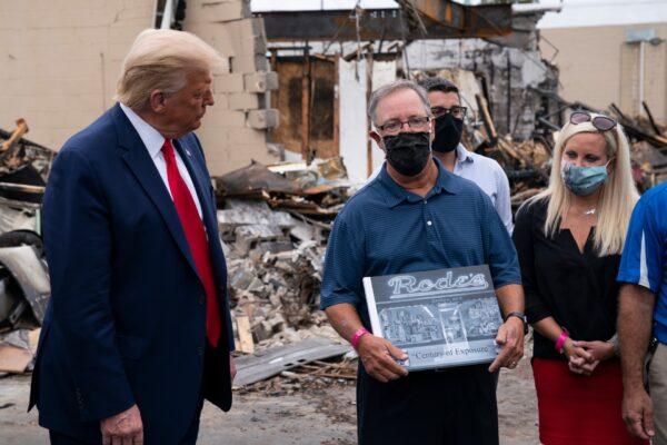 President Donald Trump talks with John Rode, the former owner of Rode’s Camera Shop, as he speaks with business owners, during a tour of an area damaged during demonstrations after a police officer shot Jacob Blake in Kenosha, Wis., on Sept. 1, 2020. (Evan Vucci/AP Photo)