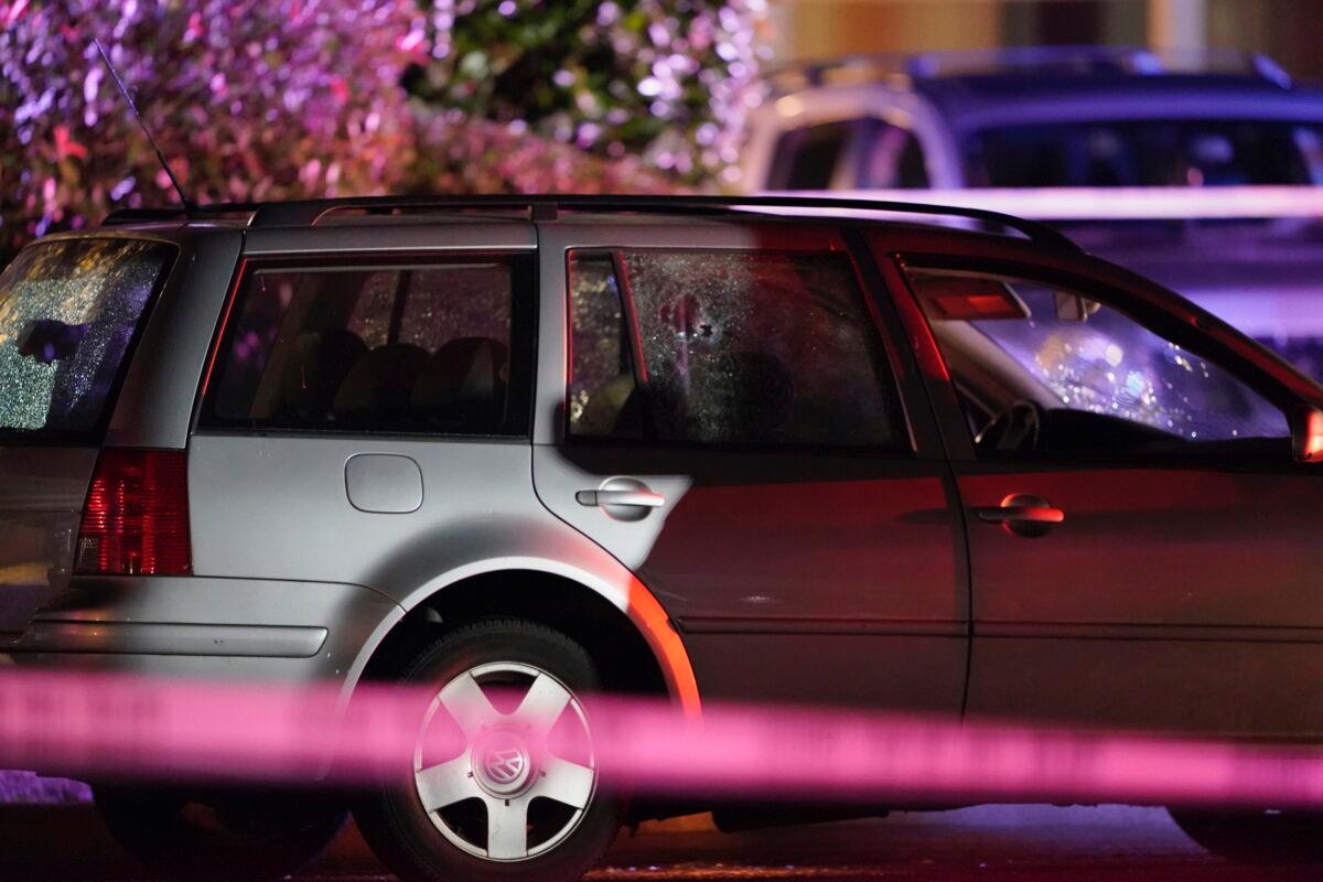 A car with shattered windows and likely bullet holes stands in the area where a man suspected of gunning down another man in Portland, Ore., over the weekend, was killed by investigators in Lacey, Wash., late Sept. 3, 2020. (Ted Warren/AP Photo)