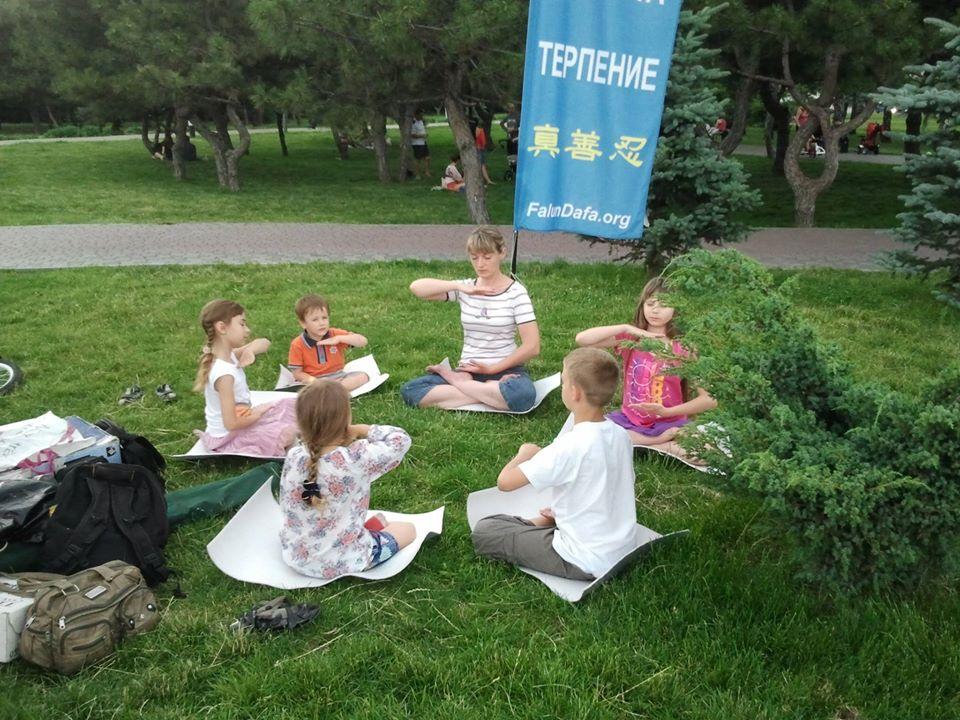 Lyudmila Orel practicing the fifth set of Falun Gong exercises with children in a park. (Courtesy of Denys Nahorniuk via Armina Nimenko)