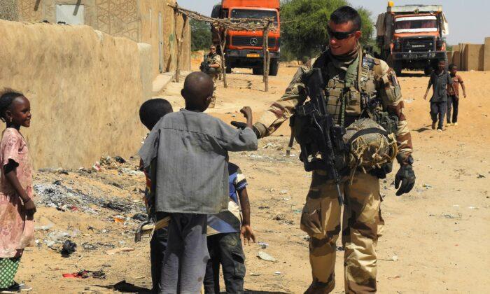 A soldier of France's Barkhane mission stands next to children as he patrols in I-n-Tillit in Mali on Nov. 1, 2017. (Daphne Benoit/AFP via Getty Images)
