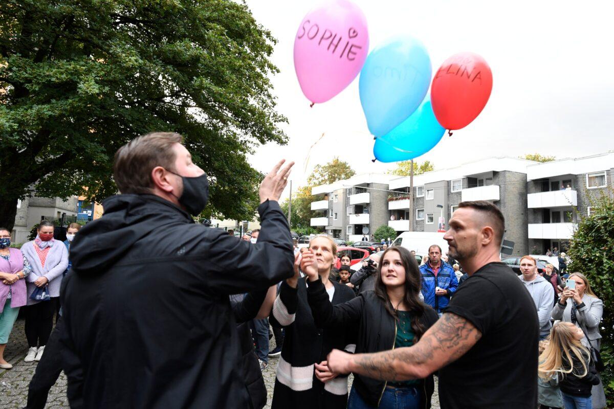 Lord Mayor Tim Kurzbach, left, and neighbours let five balloons with the names of the five killed children rise in front of the family's house as an expression of their grief in Solingen, Germany, on Saturday, Sept. 5, 2020. (Roberto Pfeil/dpa via AP)