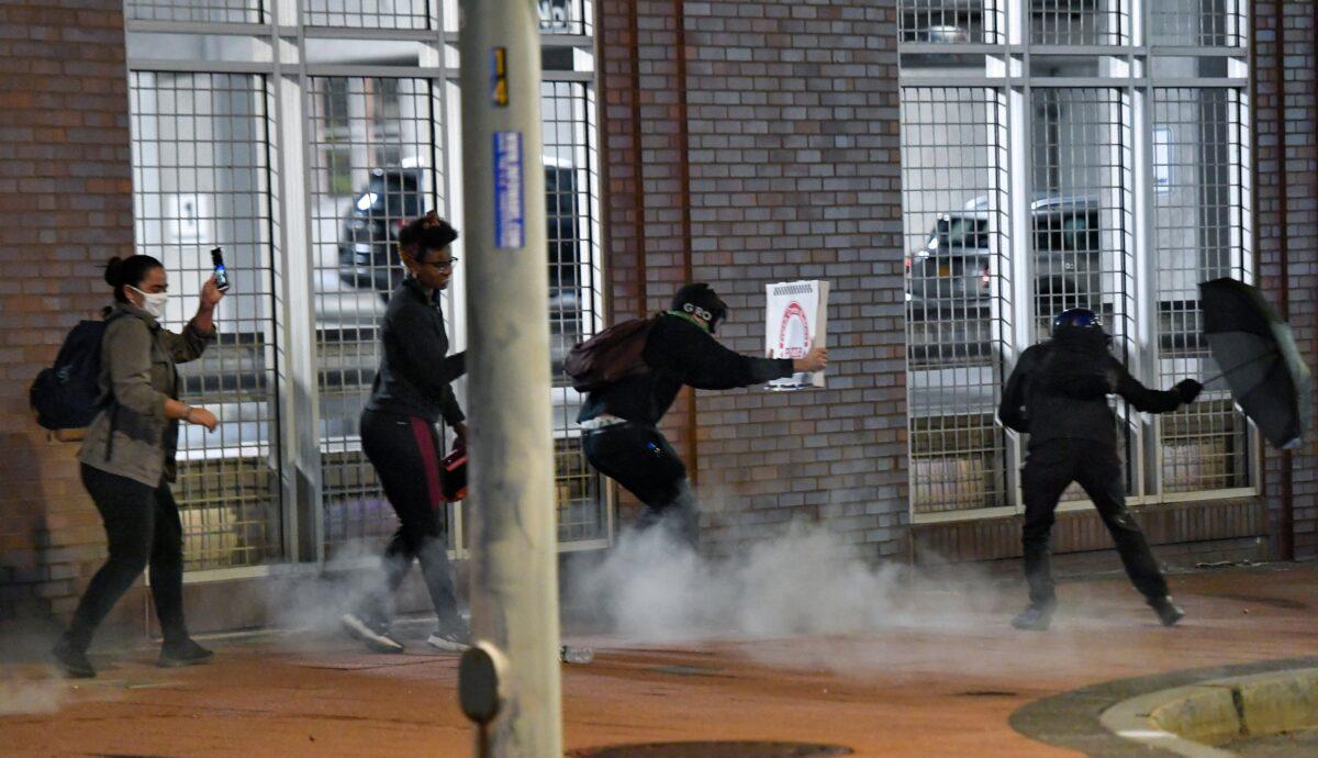 Demonstrators react to pepper balls fired by police near the Public Safety Building in Rochester, N.Y., on Friday, Sept. 4, 2020. (Adrian Kraus/AP Photo)
