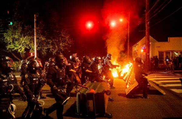 Police officers pass a fire lit by rioters in Portland, Ore. on Sept. 5, 2020. (Noah Berger/AP Photo)