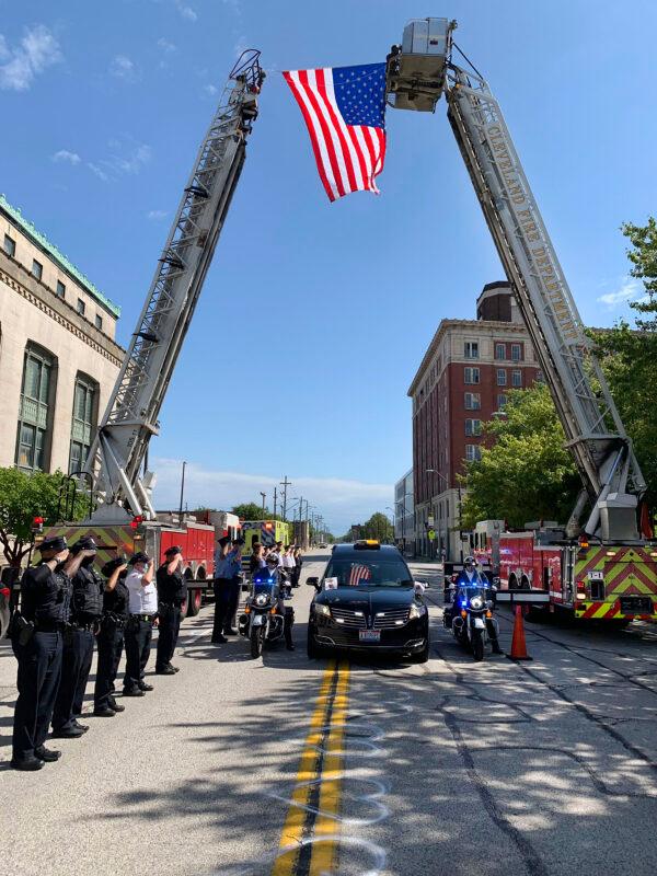 A hearse bearing the body of Det. James Skernivitz, passes under an arch made by two Cleveland Division of Fire fire engines, as it proceeds to the funeral home under police escort in Cleveland, Ohio, on Sept. 5, 2020. (Lt. Mike Norman/Cleveland Division of Fire via AP)