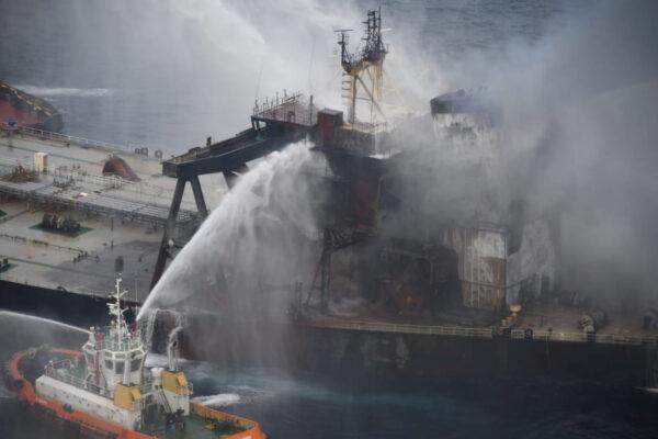 A Sri Lankan Navy boat sprays water on the New Diamond, a very large crude carrier (VLCC) chartered by Indian Oil Corp (IOC), that was carrying the equivalent of about 2 million barrels of oil, after a fire broke out off east coast of Sri Lanka, on Sept. 8, 2020. (Sri Lankan Airforce media/Handout via Reuters)