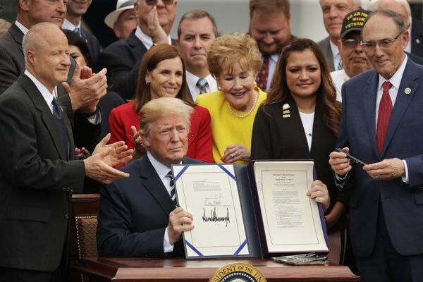 President Donald Trump holds up the Veterans Affairs Mission Act he signed during a ceremony with members of Congress and veterans in the Rose Garden at the White House in Washington, on June 6, 2018. (Chip Somodevilla/Getty Images)