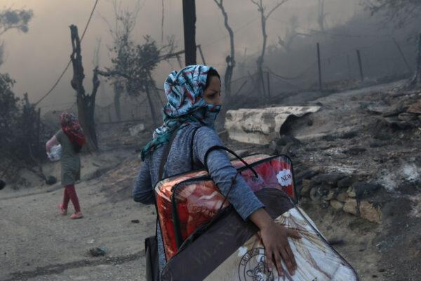 A migrant carries her belongings following a fire at the Moria camp for refugees and migrants on the island of Lesbos, Greece, on Sept. 9, 2020. (Elias Marcou/Reuters)