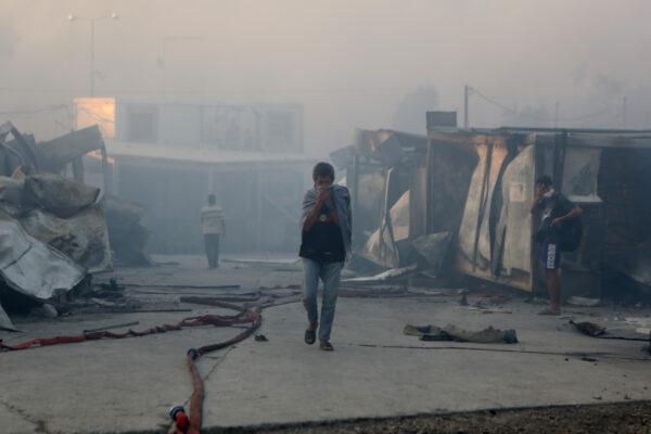 Migrants walk among destroyed shelters following a fire at the Moria camp on the island of Lesbos, Greece, on Sept. 9, 2020. (Elias Marcou/Reuters)