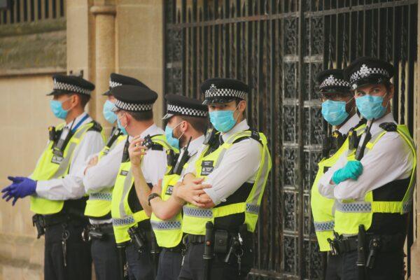 Police officers stand wearing masks as a precaution against the transmission of the CCP virus, in London on Sept. 9, 2020. (Isabel Infantes/AFP via Getty Images)