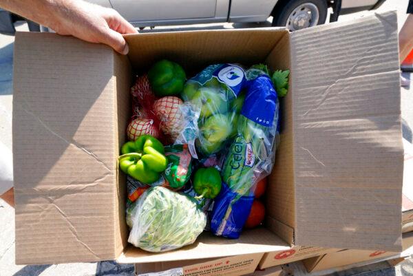 A volunteer shows a box filled with produce to be given away at a drive-up produce giveaway organized by a Des Moines food pantry on Aug. 28, 2020, in Des Moines, Iowa. (AP Photo/Charlie Neibergall)