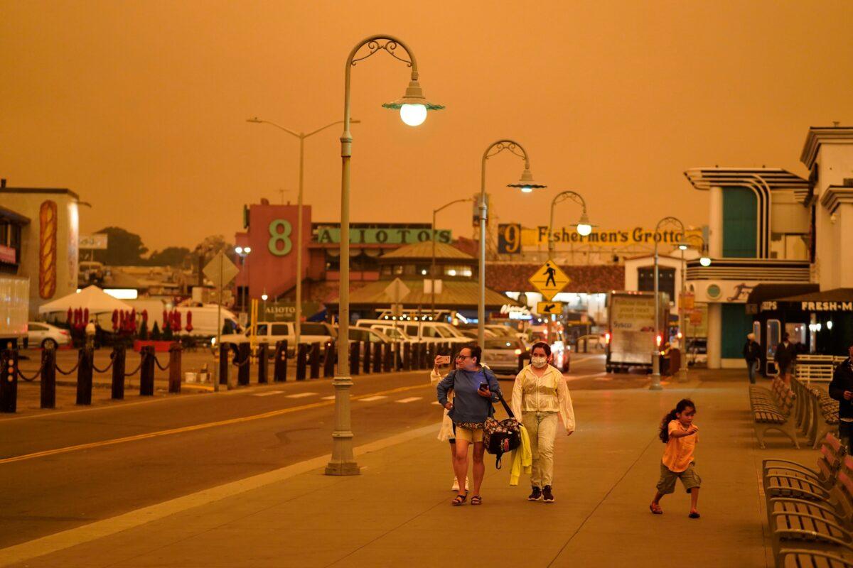 Under darkened skies from wildfire smoke, people walk at Fisherman's Wharf in San Francisco, Calif., on Sept. 9, 2020. (The picture was taken in the middle of the day at 1:01 p.m.) (Eric Risberg/AP Photo)