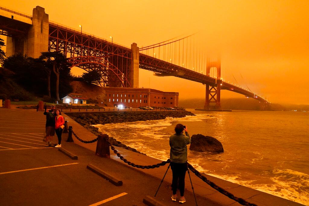 People stop at Fort Point to take morning pictures of the Golden Gate Bridge covered in smoke from wildfires Wednesday, Sept. 9, 2020, in San Francisco. (Eric Risberg/AP)
