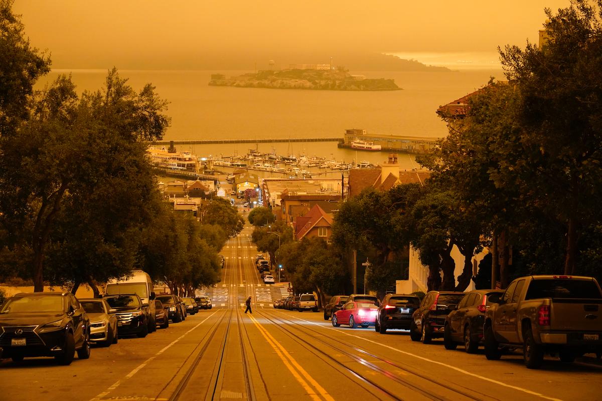 Under darkened skies from wildfire smoke, a man crosses Hyde Street with Alcatraz Island and Fisherman’s Wharf in the background on Wednesday, Sept. 9, 2020, in San Francisco. (Eric Risberg/AP)