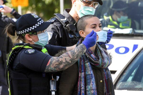 Police place a face mask on an arrested protester at the Shrine of Remembrance in Melbourne on Sept. 5, 2020 during an anti-lockdown rally protesting the state's strict lockdown laws as a preventive measure against the COVID-19 coronavirus. (William West / AFP via Getty Images)