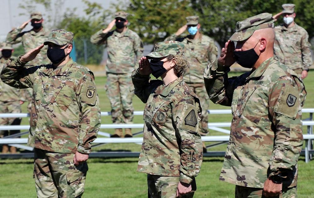 Maj. Krystian Derda (L), Lt. Col. Kristin Derda (C), and Brig. Gen. Dan Dent (R) salute the flag prior to the Derdas' joint promotion ceremony on Sept. 3, 2020. (<a href="https://www.dvidshub.net/image/6338858/joint-promotion-ceremony-special-washington-guard-family">Joseph Siemandel</a>/U.S. National Guard)