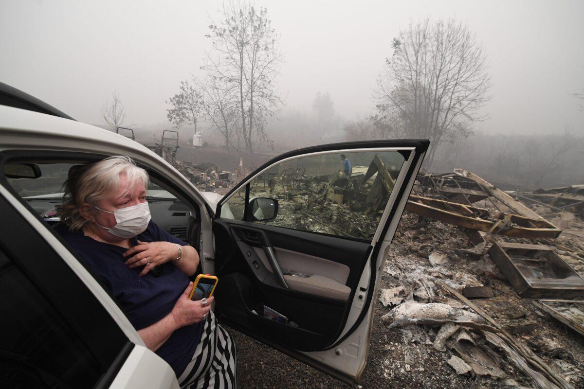 Margi Wyatt reacts after returning to find her mobile home destroyed by wildfire as her husband Marcelino Maceda (background) searches in the ruins in Estacada, Ore., on Sept. 12, 2020. (Robyn Beck/AFP via Getty Images)