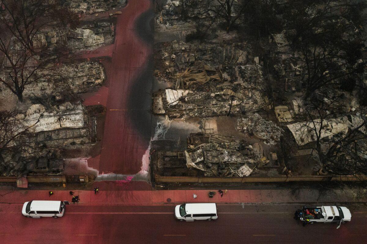 A search and rescue team, surrounded by red fire retardant, is seen near burned residences and vehicles in the aftermath of the Almeda fire in Talent, Ore., on Sept. 13, 2020. (Adrees Latif/Reuters)