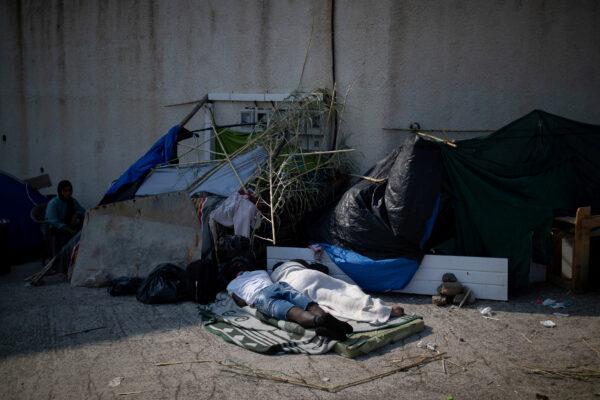 Two men sleep as migrants from the destroyed Moria camp are sheltered near a new temporary camp, on the island of Lesbos, Greece, on Sept.15, 2020. (Alkis Konstantinidis/Reuters)