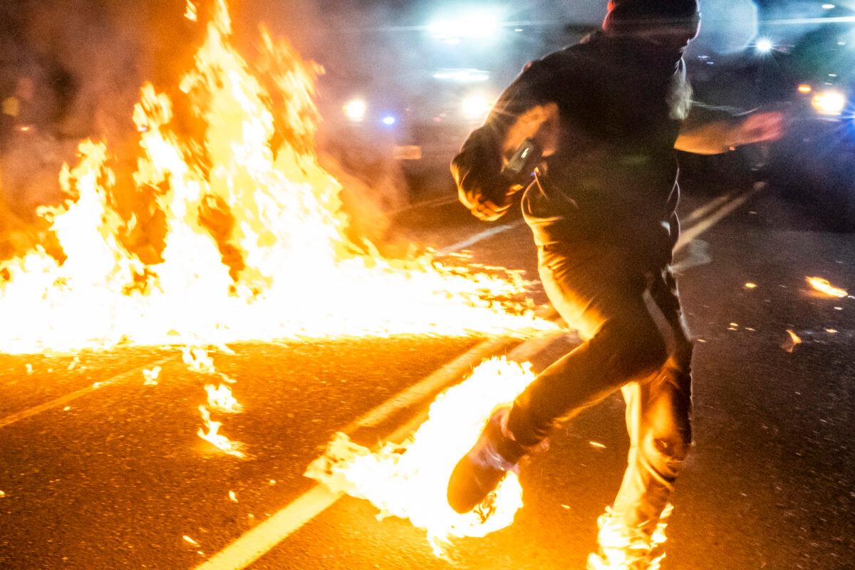 An individual whose feet caught fire after a molotov cocktail exploded during a riot runs toward a medic in Portland, Ore., on Sept. 5, 2020. (Nathan Howard/Getty Images)
