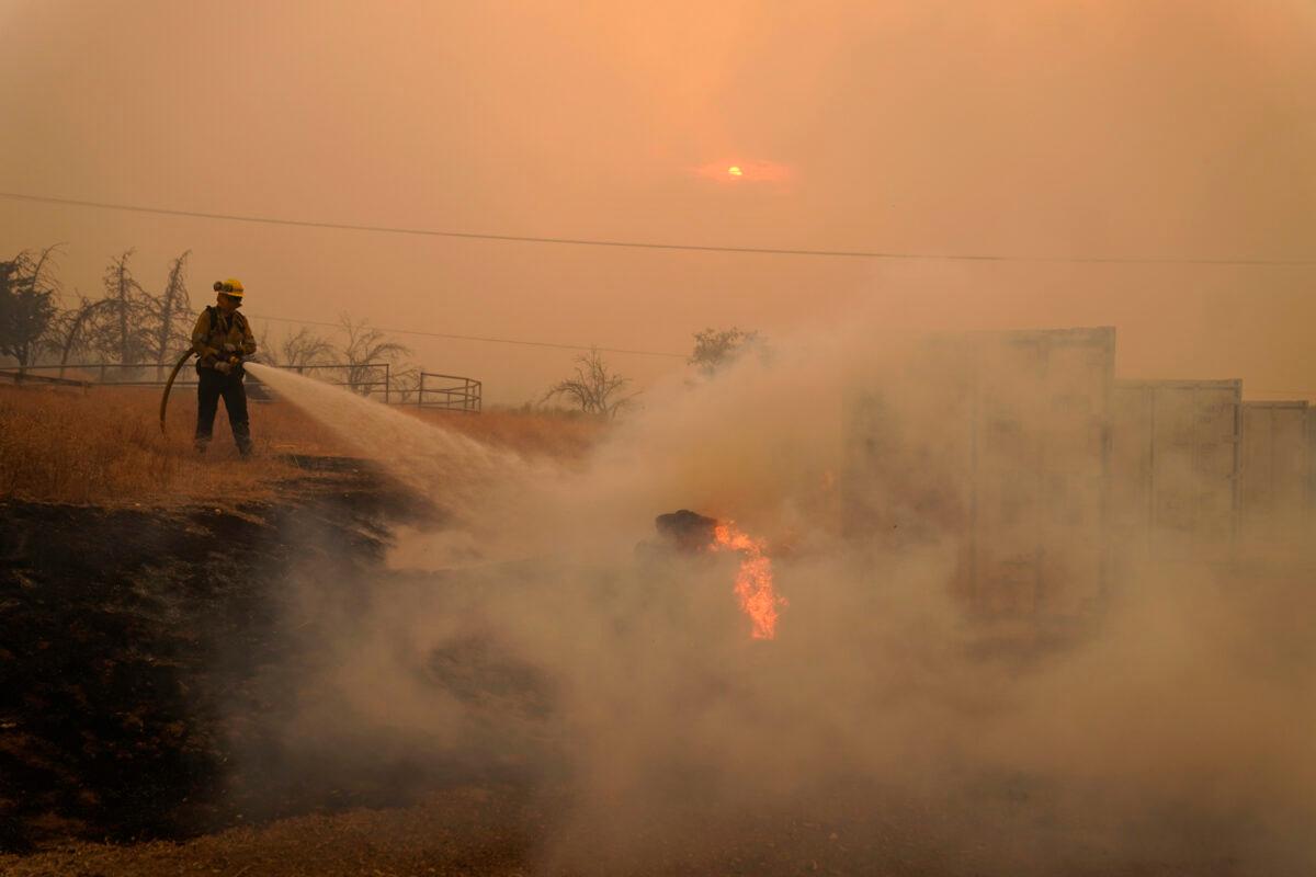 A member of a Los Angeles County Fire crew hoses down flames while protecting a home from the advancing Bobcat Fire along Cima Mesa Rd. in Juniper Hills, Calif., on Sept. 18, 2020. (Marcio Jose Sanchez/AP Photo)