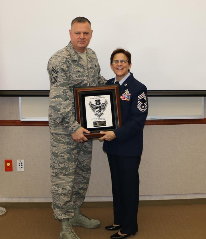 Air Force Command Chief Master Sgt. Richard King presents a plaque to Dooley as she leaves EADS to become the Command Chief Master Sgt. of the New York Air National Guard on Feb. 2, 2018. (<a href="https://www.dvidshub.net/image/4117366/conr-1af-chief-presents-plaque-outgoing-eads-chief">Timothy Jones</a>/DVIDSHUB)