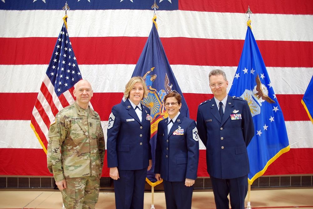 The New York Army National Guard's Command Sergeant Major CSM David Piwowarski (L), Command Chief Master Sergeant CMSgt. Amy R. Giaquinto (L–center), and New York Adjutant General MG Anthony German (R) pose with Dooley at a Change of Responsibility ceremony held at the Division of Military and Naval Affairs on Feb. 26, 2018 (<a href="https://www.dvidshub.net/image/4169778/ny-air-guard-change-authority-ceremony">William Albrecht</a>/DVIDSHUB)