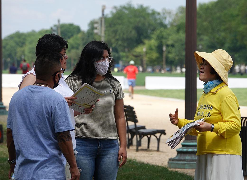 Wang Chunrong (R) telling a group of tourists about Falun Gong and its persecution at the National Mall in Washington on July 4, 2020. (©<a href="https://en.minghui.org/html/articles/2020/7/6/185778.html">Minghui</a>)