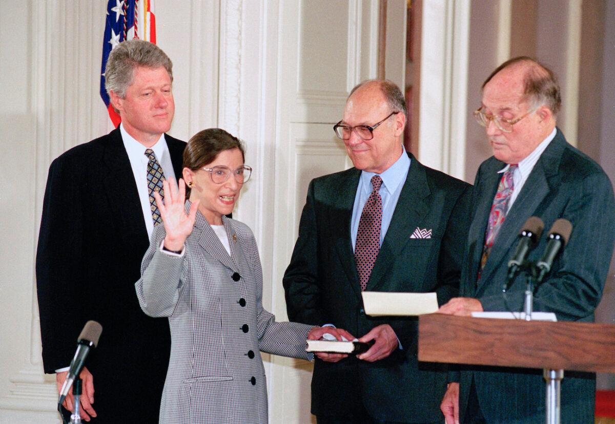 Supreme Court Justice Ruth Bader Ginsburg takes the court oath from Chief Justice William Rehnquist, right, during a ceremony in the East Room of the White House in Washington. Ginsburg's husband Martin holds the Bible and President Bill Clinton watches at left, on Aug. 10, 1993. (AP Photo/Marcy Nighswander, File)