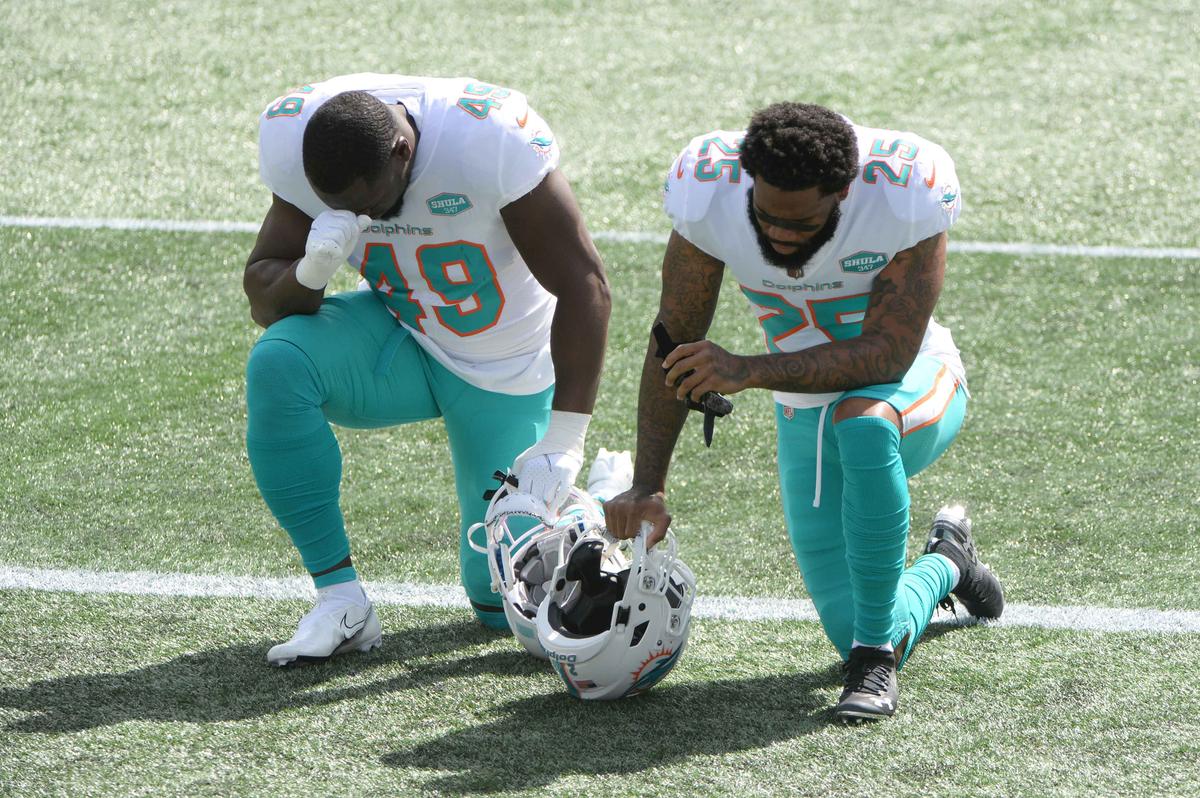 Sam Eguavoen #49 and Xavien Howard #25 of the Miami Dolphins kneel before the game against the New England Patriots at Gillette Stadium on September 13, 2020 in Foxborough, Massachusetts. (Kathryn Riley/Getty Images)