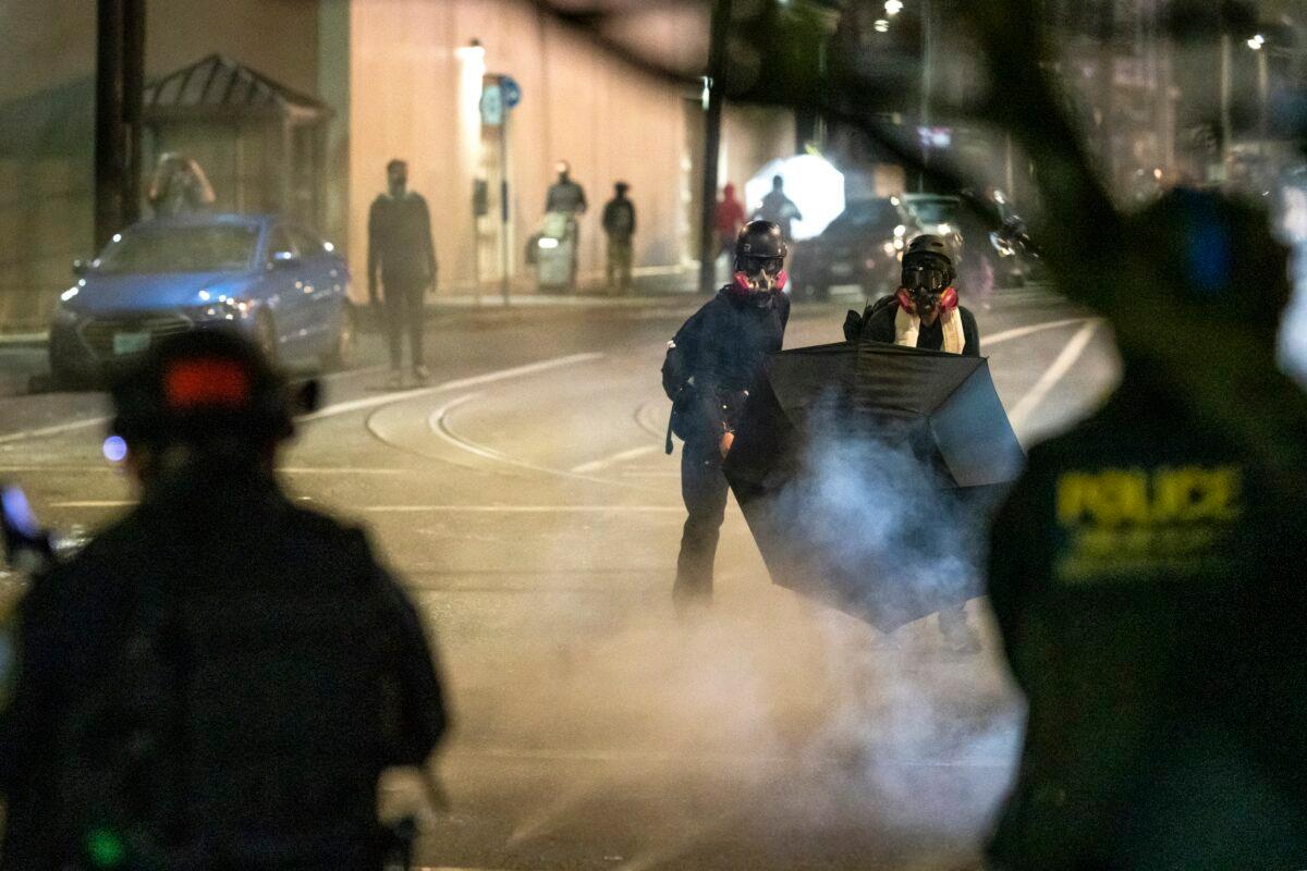 People use umbrellas to block less-lethal rounds fired by federal officers during an unlawful assembly at the Immigration and Customs Enforcement detention center in Portland, Ore., on Sept. 18, 2020. (Nathan Howard/Getty Images)