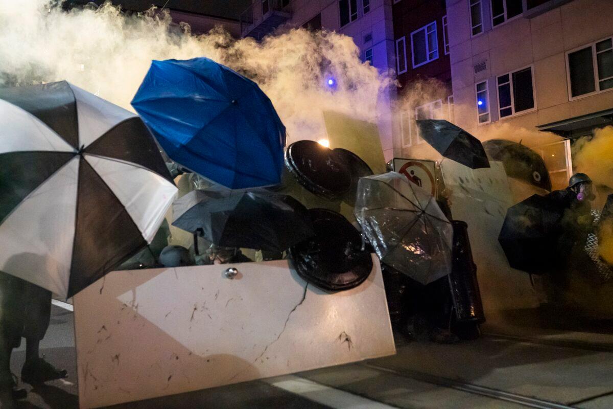 Protesters use umbrellas to block less-lethal rounds fired by federal officers during a dispersal at the Immigration and Customs Enforcement detention center in Portland, Ore., on Sept. 18, 2020. (Nathan Howard/Getty Images)