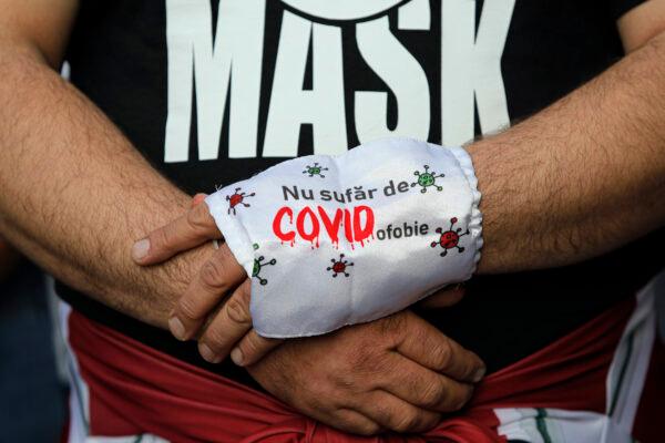A man holds a sign saying "I don't suffer from COVID-ophobia" during a protest in Bucharest, on Sept. 19, 2020. (Vadim Ghirda/AP Photo)